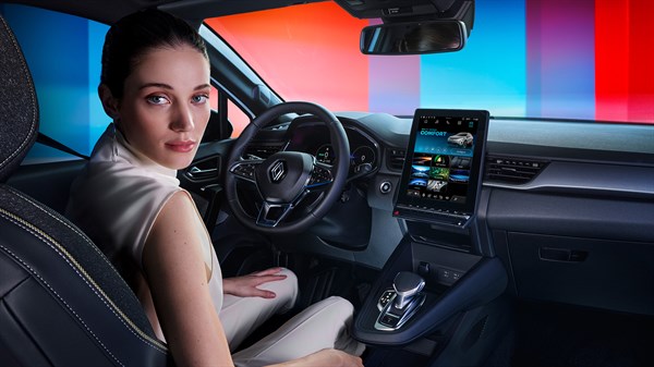 Žena sjedi u modernoj unutrašnjosti automobila Renault Captur s velikim ekranom na središnjoj konzoli.